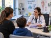NRW’de acil servis istasyonlarının geleceği tartışılıyor Doktor masa başında hasta ile tıbbi belgeleri inceliyor.