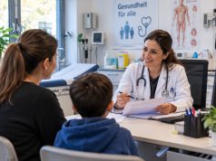 NRW’de acil servis istasyonlarının geleceği tartışılıyor Doktor masa başında hasta ile tıbbi belgeleri inceliyor.
